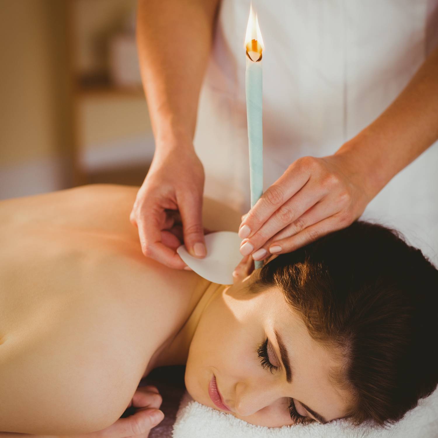 An ear candling session, the candle held upright with a protective disc